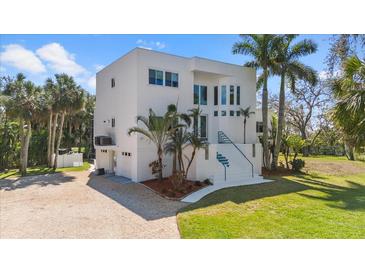 Stunning modern two-story home featuring a clean white facade, landscaped yard, and tropical palm trees at 375 Wellington Ave, Oldsmar, FL 34677