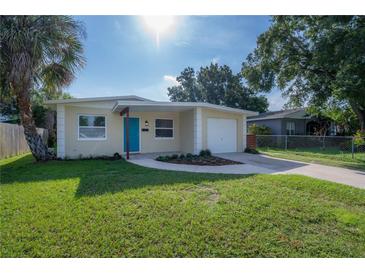 Charming home featuring a well-manicured lawn, complemented by a colorful door and a single-car garage at 6610 S Mascotte St, Tampa, FL 33616