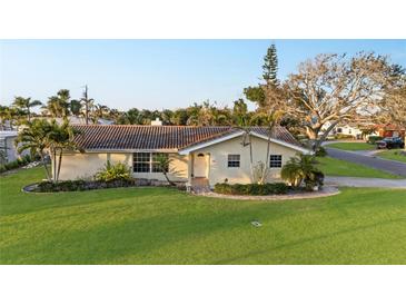 Charming single-story home with well-maintained lawn, mature trees, and a welcoming front entrance at 111 22Nd St, Belleair Beach, FL 33786