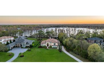 Stunning aerial view of a lakeside home with lush green lawn, mature trees, and a beautiful water view at 5914 Fitzgerald Rd, Odessa, FL 33556