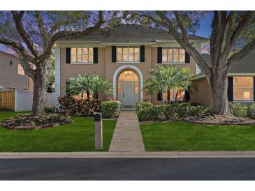 Charming two-story home featuring lush landscaping, mature trees, and a welcoming front entrance at 902 Marco Ne Dr, St Petersburg, FL 33702