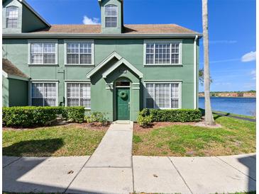 Green two-story townhome with a well-maintained lawn and walkway leading to the front door by the water at 9730 Lake Chase Island Way # 9730, Tampa, FL 33626