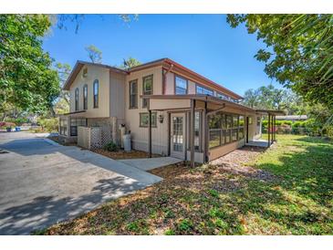 Two-story home featuring a tan exterior, screened patio, and lush surrounding greenery at 2903 Oak Crest Dr, Plant City, FL 33565