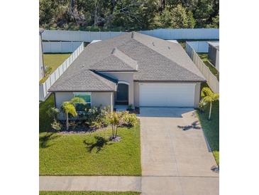Well-maintained single-story home features a manicured lawn, long driveway, and white fenced in backyard at 6494 Beverly Hills Dr, Zephyrhills, FL 33541