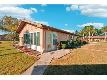 Charming single-story home featuring a well-maintained lawn, walkway and a cozy enclosed porch area at 1904 Canterbury Ln # 21, Sun City Center, FL 33573