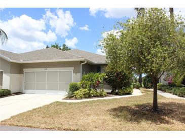 Charming single-story home with a well-manicured lawn and beautiful landscaping, including colorful shrubs and a mature shade tree at 2129 Acadia Greens Dr, Sun City Center, FL 33573