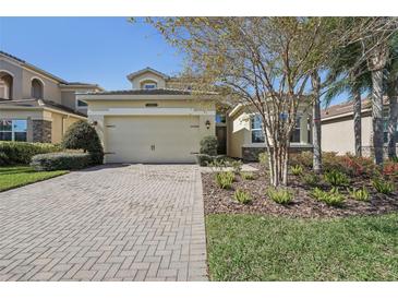 Charming home with a brick driveway, a two-car garage, and manicured landscaping at 30280 Southernwood Ct, Wesley Chapel, FL 33543