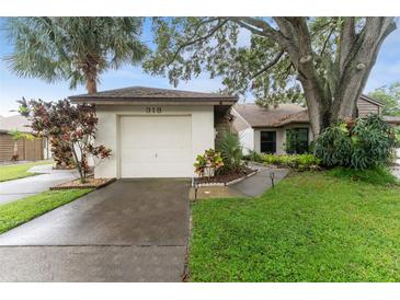 Charming single Gathering home showcasing a well manicured lawn and attached one car garage at 318 Parkside Ln, Safety Harbor, FL 34695