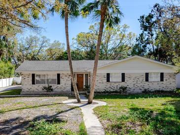 Charming single-story brick home with symmetrical facade, manicured lawn, and mature trees at 4820 W San Miguel St, Tampa, FL 33629