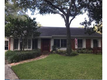 Charming single-story brick home with a lush green lawn and mature trees providing ample shade at 5110 W Evelyn Dr, Tampa, FL 33609