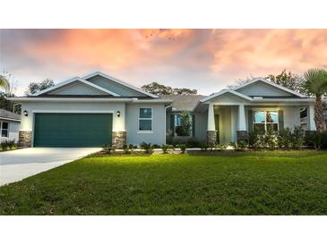 Charming single-story home with a well-manicured lawn, a two-car garage and a picturesque sky in the background at 59 Mark Twain Ln, Rotonda West, FL 33947