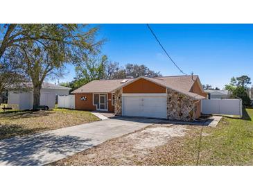 Cozy single-story home featuring a stone-accented facade and a large, attached two-car garage with long driveway at 12256 Katherwood St, Spring Hill, FL 34608