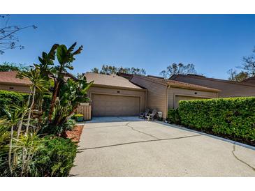 Charming villa featuring lush landscaping and a two-car garage on a sunny day at 30 Woodridge Cir, Oldsmar, FL 34677