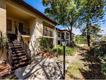 Inviting condo exterior showcasing stairs to units, mature landscaping, and pathways, offering a serene living environment at 3389 Crystal E Ct # M, Palm Harbor, FL 34685