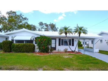 Charming single-story home with a white exterior, well-manicured lawn, and mature landscaping featuring palm trees at 4517 100Th N Ave, Pinellas Park, FL 33782