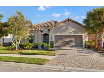 Charming single-story home with a well-manicured lawn, brick driveway, and a two-car garage at 9708 Highland Park Pl, Palmetto, FL 34221