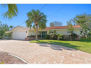 Charming single-story home with well-maintained landscaping and a brick-paved driveway, all under a bright blue sky at 222 Mar St, St Pete Beach, FL 33706
