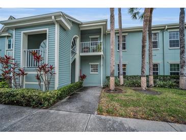 Inviting exterior of the two-story home with beautiful balconies, landscaping, and palm trees at 240 Promenade Dr # 102, Dunedin, FL 34698