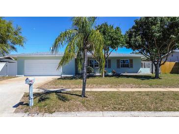 Charming single-story home featuring a well-manicured lawn and beautiful landscaping at 10915 Hammock Dr, Largo, FL 33774