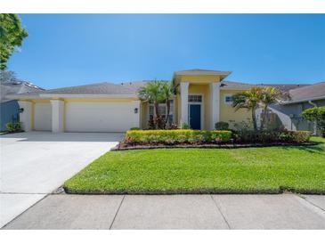 Inviting one-story home featuring a well-manicured lawn and two-car garage at 12406 Bristol Commons Cir, Tampa, FL 33626