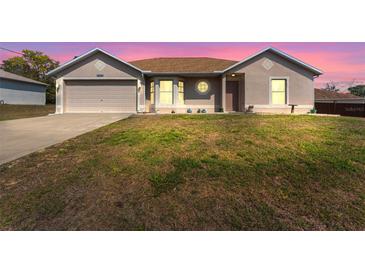 Charming single-story home featuring a manicured lawn and attached two-car garage at dusk at 13191 Siam Dr, Spring Hill, FL 34609