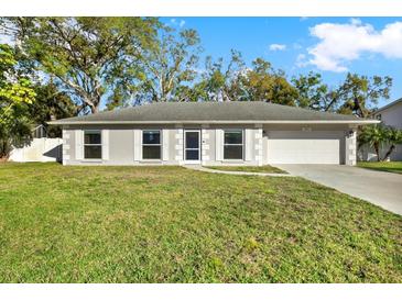 Inviting single-story home with a two-car garage, mature landscaping, and a well-maintained lawn at 13911 Briardale Ln, Tampa, FL 33618
