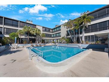 Relaxing community pool surrounded by lush landscaping at this condo complex with lounge chairs at 215 Valencia Blvd # 205, Belleair Bluffs, FL 33770