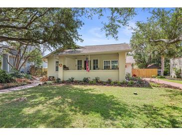Charming single-story home featuring a well-manicured lawn, lush landscaping, and inviting covered front porch at 235 Aberdeen St, Dunedin, FL 34698