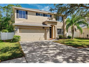 Two story home featuring a two car garage, neutral paint, dark shutters, landscaped yard and mature trees at 4821 Barchetta Dr, Land O Lakes, FL 34639