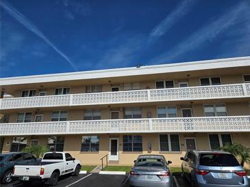 Three-story condo building with covered balconies and ample parking under a blue sky at 5095 Bay Ne St # 310, St Petersburg, FL 33703