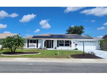 Charming home featuring solar panels, a well-manicured lawn, and a two-car garage at 663 Allegheny Dr, Sun City Center, FL 33573