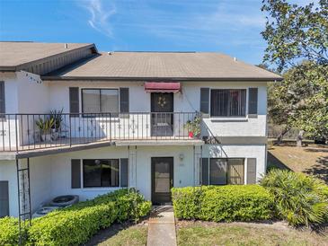 Two-story condo featuring a balcony, black shutters, and manicured landscaping at 6701 River Run Blvd, Weeki Wachee, FL 34607