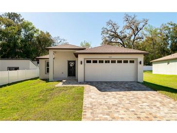 Charming single-story home featuring a brick-paved driveway, manicured lawn, and a two-car garage at 818 S Main St, Brooksville, FL 34601