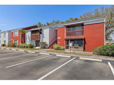 Red brick two-story condo building with a parking lot and well-maintained landscaping on a bright, sunny day at 1055 82Nd N Ter # 1055A, St Petersburg, FL 33702