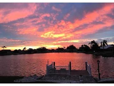 Beautiful water view from the house featuring a dock and a fiery sunset backdrop at 1710 New Bedford Dr, Sun City Center, FL 33573