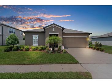 Beautiful single-story home with a well-manicured lawn, mature landscaping and a two-car garage at 18414 Malinche Loop, Spring Hill, FL 34610