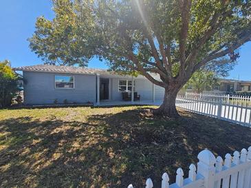 A lovely home exterior with a mature tree, white picket fence, and well-maintained lawn at 3136 Primrose Dr, Holiday, FL 34691