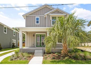Charming two-story home featuring a welcoming front porch, landscaped yard, and a beautiful palm tree at 410 W Paris St, Tampa, FL 33604