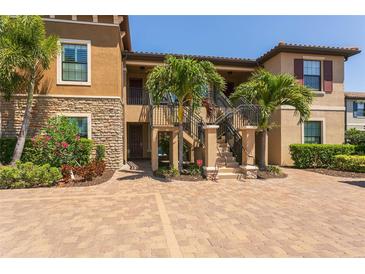 Charming two-story condo featuring a stone facade, lush landscaping, and a private entrance with well-maintained stairs at 5420 Cicerone St # 103, Sarasota, FL 34238