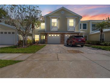 Charming townhome featuring a paver driveway, two-car garage, and manicured landscaping at 914 Woodbridge Ct, Safety Harbor, FL 34695