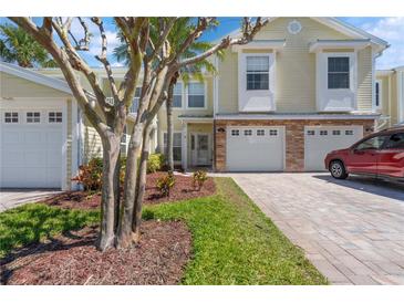 Charming townhome featuring a brick-accented facade, a paver driveway, and mature landscaping in the front yard at 914 Woodbridge Ct, Safety Harbor, FL 34695