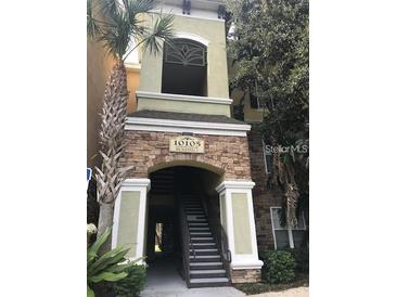 Inviting building entrance with stacked stone facade and stairs leading to upper level units at 10105 Courtney Oaks Cir # 101, Tampa, FL 33619