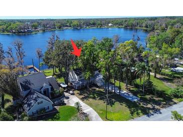 Stunning lakefront property with lush greenery and a charming two-story home nestled among the trees at 18715 Lakeshore Dr, Lutz, FL 33549
