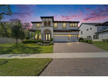 Elegant two-story home featuring a three-car garage, lush landscaping, and a paver driveway at 2911 Silva Wood Dr, Valrico, FL 33596