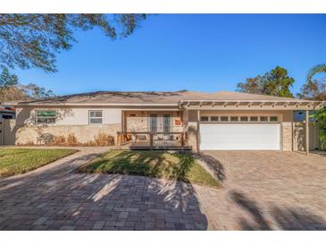 Charming single-story home featuring stone accents, a brick driveway, and a well-manicured lawn at 7039 Hibiscus S Ave, South Pasadena, FL 33707