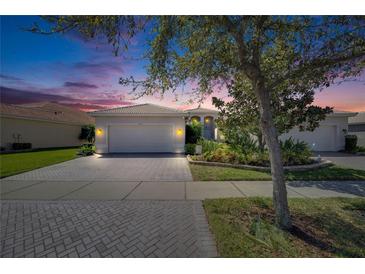 Charming single Gathering home with tile roof, landscaping, brick driveway, and two car garage at 15657 Aurora Lake Cir, Wimauma, FL 33598