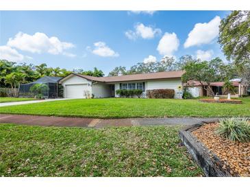 Well-maintained single-story home features a lush lawn, mature trees, and a screened-in lanai at 1830 Oak Forest S Dr, Clearwater, FL 33759