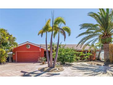 Charming one-story home with a red exterior, tile roof, and lush tropical landscaping at 351 S Julia Cir, St Pete Beach, FL 33706