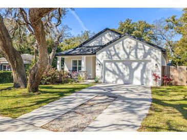 Charming home features a two-car garage, beautifully landscaped front yard, and a welcoming front porch at 9310 N Willow Ave, Tampa, FL 33612