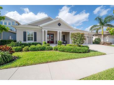 Charming one-story home featuring a manicured lawn, lush landscaping, and a welcoming covered front porch at 6915 Sea Stone Ct, Apollo Beach, FL 33572